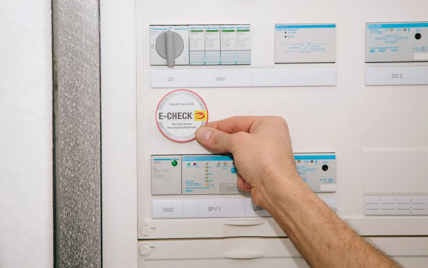 E-CHECK - Mitarbeiter klebt in der Verteilung die E-CHECK Plakette an · Degen