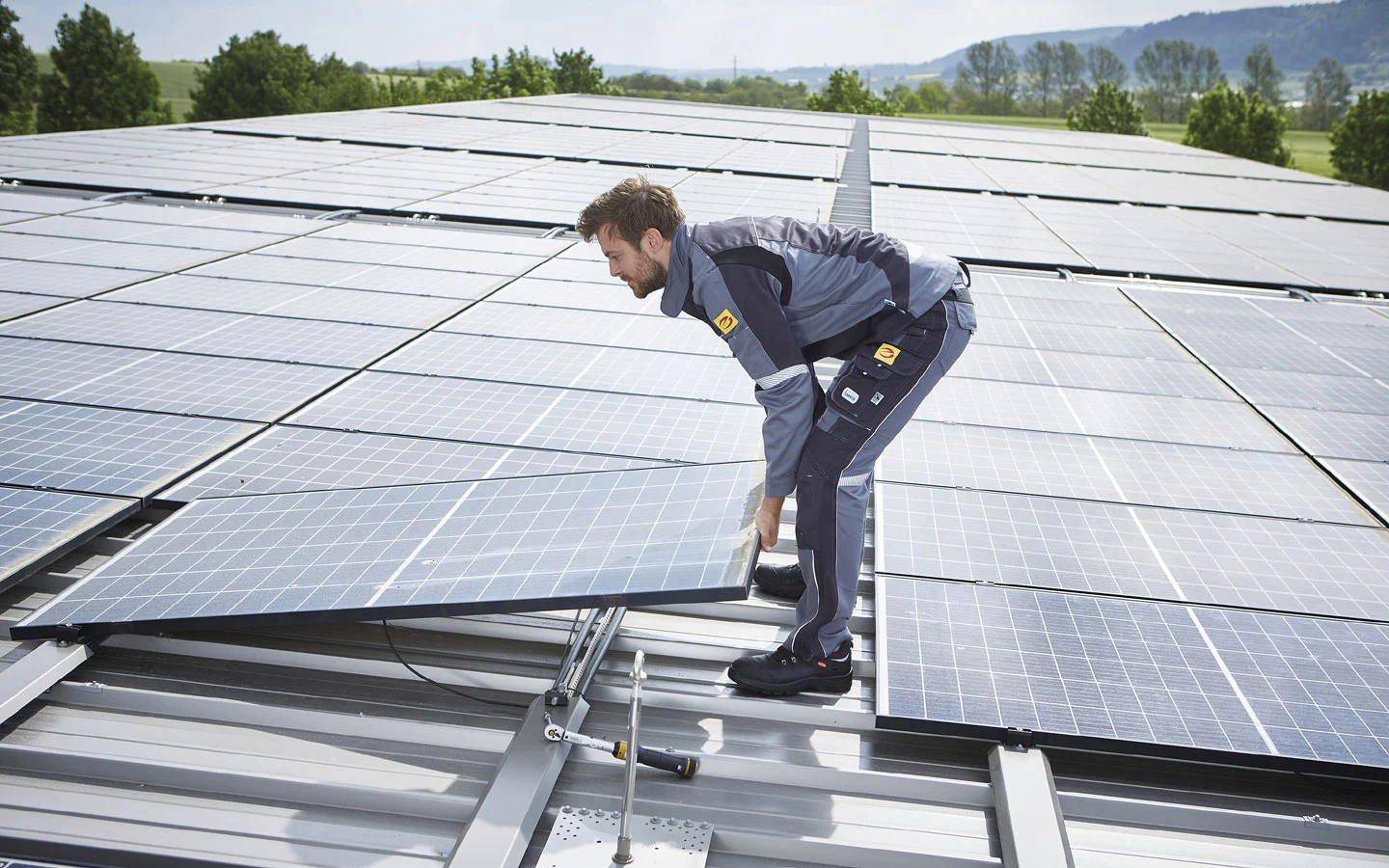 E-CHECK PV - Mitarbeiter installiert Solarzellen auf dem Dach · Degen